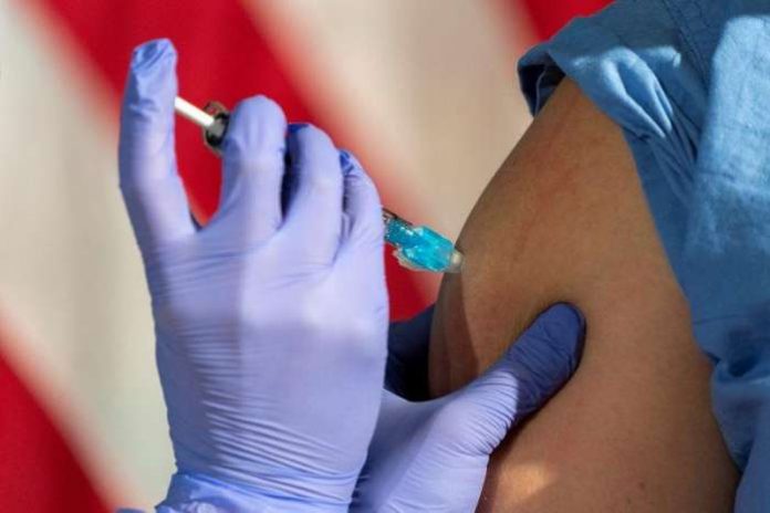 In front of an American flag, nurse Lillian Wirpsza administers a COVID-19 vaccine to Shylee Stewart, a labor and delivery nurse at George Washington University Hospital, in Washington, D.C., U.S. December 14, 2020. Jacquelyn Martin-Pool via REUTERS In front of an American flag, nurse Lillian Wirpsza administers a COVID-19 vaccine to Shylee Stewart, a labor and delivery nurse at George Washington University Hospital, in Washington, D.C., U.S. December 14, 2020. Jacquelyn Martin-Pool via REUTERS