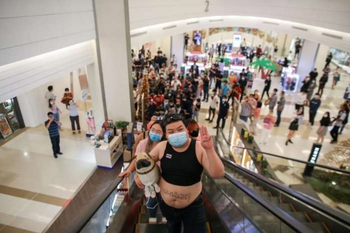 Protest leaders Panusaya Rung Sithijirawattanakul and Parit Penguin Chiwarak wearing crop tops ride on an escalator at Siam Paragon shopping centre, as they demonstrate against the monarchy, in Bangkok, Thailand, December 20, 2020. REUTERS