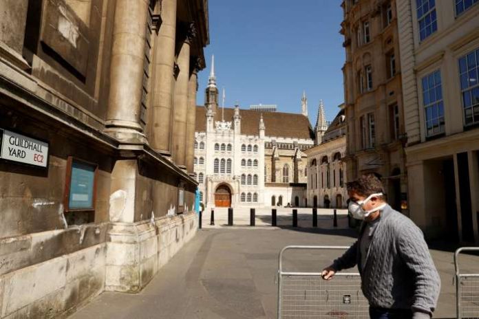 FILE PHOTO - A man wearing a mask outside Guildhall in the city of London as the spread of the coronavirus disease (COVID-19) continues, London, Britain, April 14, 2020. REUTERS-John Sibley-File Photo FILE PHOTO - A man wearing a mask outside Guildhall in the city of London as the spread of the coronavirus disease (COVID-19) continues, London, Britain, April 14, 2020. REUTERS-John Sibley-File Photo