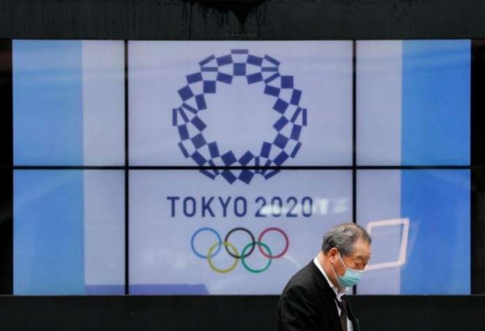 FILE PHOTO- A passerby wearing a protective face mask walks past a screen showing the logo of the 2020 Olympic Games in Tokyo, Japan, April 14, 2021. REUTERS-Issei Kato FILE PHOTO- A passerby wearing a protective face mask walks past a screen showing the logo of the 2020 Olympic Games in Tokyo, Japan, April 14, 2021. REUTERS-Issei Kato